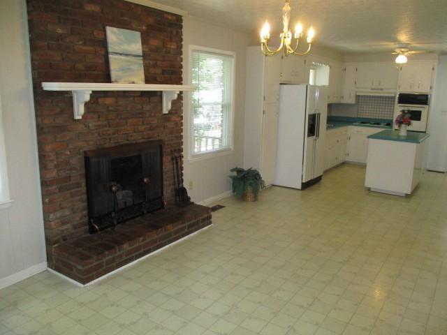 829 Kenny St, Gallatin, TN 37066 - kitchen with white appliances, a chandelier, white cabinetry, light floors, and a brick fireplace