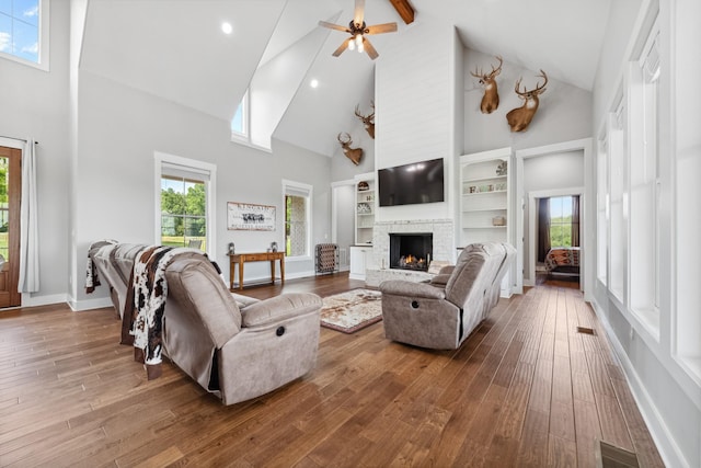 5247 Flat Creek Rd, Spring Hill, TN 37174 - living room featuring high vaulted ceiling, a warm lit fireplace, wood-type flooring, ceiling fan, and built in shelves