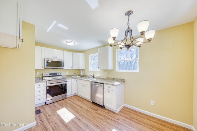 1112 Brookside Ave, Maryville, TN 37804 - kitchen featuring stainless steel appliances, light wood-style flooring, a chandelier, white cabinets, and light stone counters