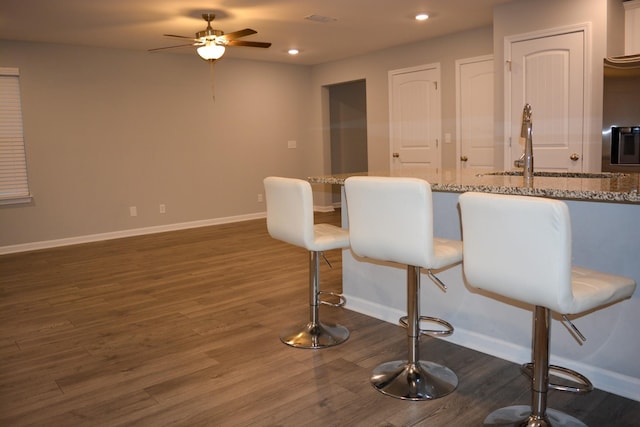 3722 Stormy Ln, Rockvale, TN 37153 - kitchen with ceiling fan, dark wood finished floors, light stone counters, a breakfast bar, and recessed lighting
