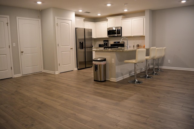 3722 Stormy Ln, Rockvale, TN 37153 - kitchen with appliances with stainless steel finishes, a peninsula, white cabinets, dark wood-type flooring, and backsplash