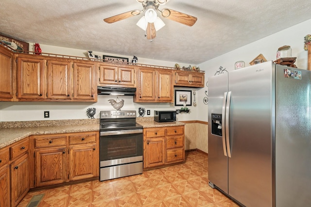 10615 Owens Chapel Rd, Springfield, TN 37172 - kitchen with stainless steel appliances, under cabinet range hood, ceiling fan, brown cabinetry, and a textured ceiling