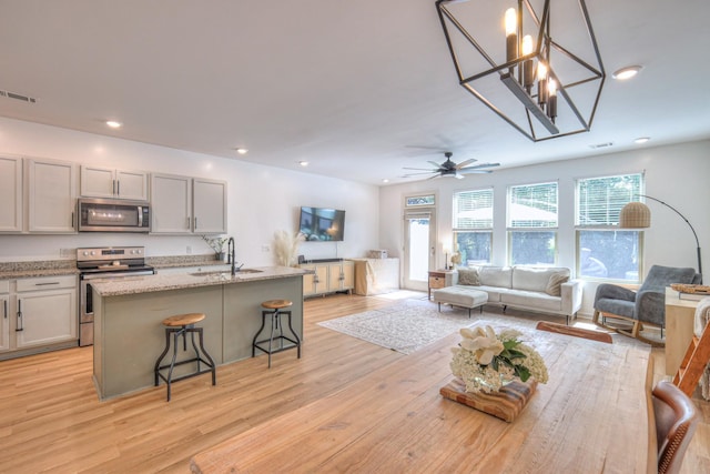 3105 Defilade Dr, Murfreesboro, TN 37128 - kitchen with stainless steel appliances, open floor plan, a breakfast bar area, light wood finished floors, and recessed lighting
