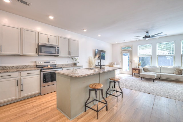 3105 Defilade Dr, Murfreesboro, TN 37128 - kitchen featuring stainless steel appliances, open floor plan, a breakfast bar area, light wood-style flooring, and an island with sink