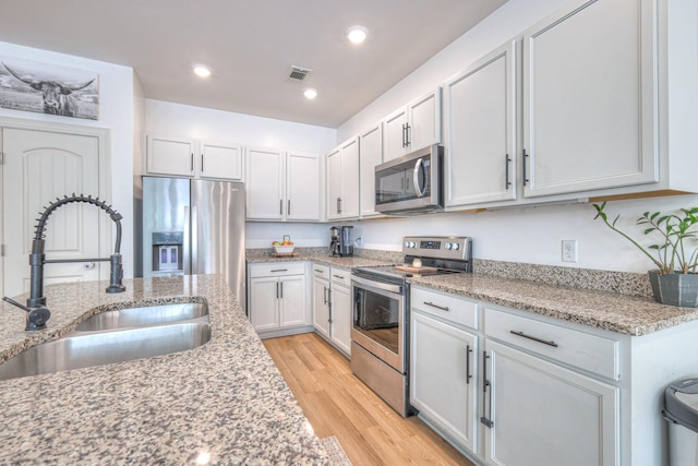 3105 Defilade Dr, Murfreesboro, TN 37128 - kitchen with appliances with stainless steel finishes, light wood finished floors, light stone counters, recessed lighting, and white cabinetry