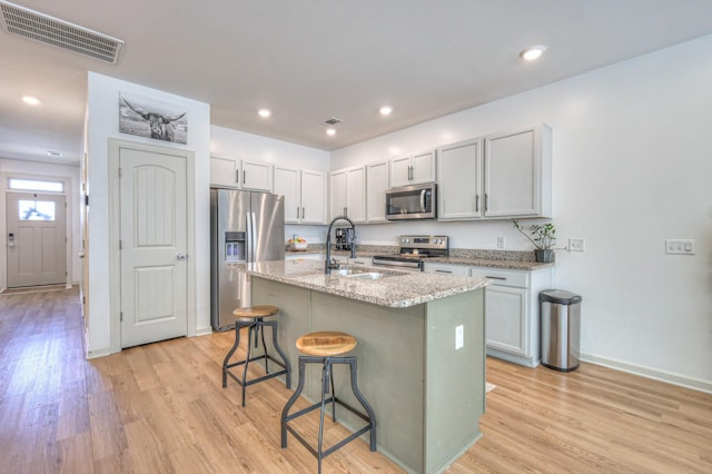 3105 Defilade Dr, Murfreesboro, TN 37128 - kitchen featuring stainless steel appliances, light wood-style flooring, a breakfast bar area, light stone countertops, and recessed lighting