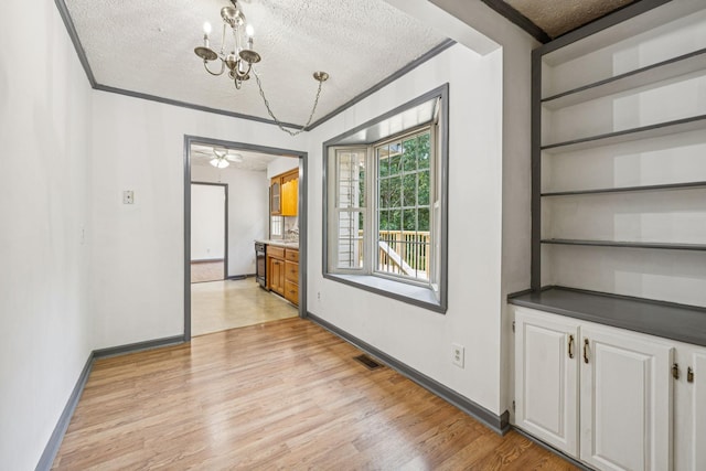 5531 Willow Oak Dr, Baxter, TN 38544 - unfurnished dining area with a textured ceiling, light wood-style flooring, ornamental molding, a chandelier, and built in features