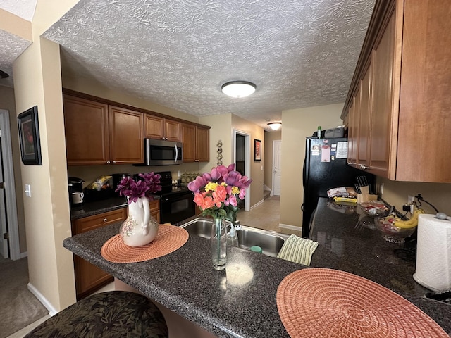 1239 Wentworth Dr, Gallatin, TN 37066 - kitchen featuring black appliances, brown cabinets, dark countertops, and a textured ceiling