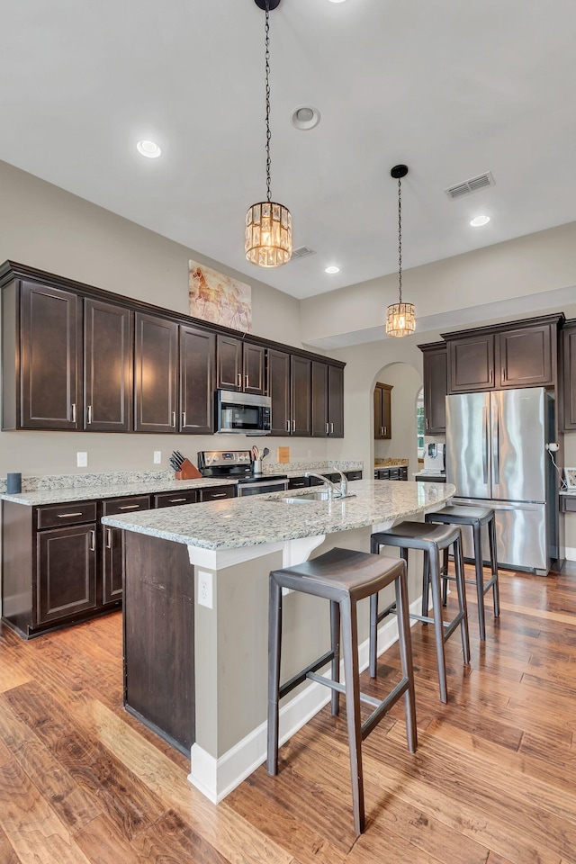1060 Harvey Springs Dr, Spring Hill, TN 37174 - kitchen with appliances with stainless steel finishes, arched walkways, dark brown cabinets, a breakfast bar area, and recessed lighting
