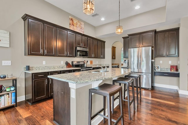 1060 Harvey Springs Dr, Spring Hill, TN 37174 - kitchen featuring stainless steel appliances, arched walkways, dark wood-style flooring, dark brown cabinetry, and decorative light fixtures