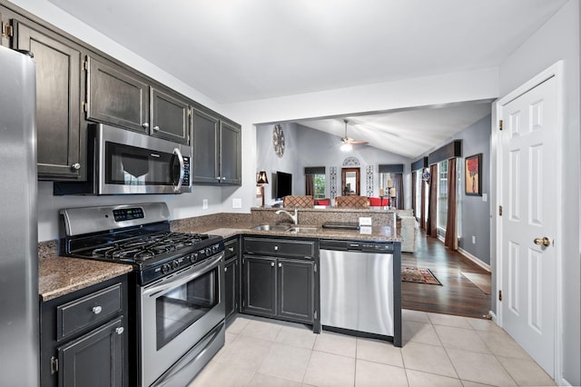 256 Granger View Cir, Franklin, TN 37064 - kitchen featuring stainless steel appliances, a peninsula, lofted ceiling, dark stone countertops, and light tile patterned flooring