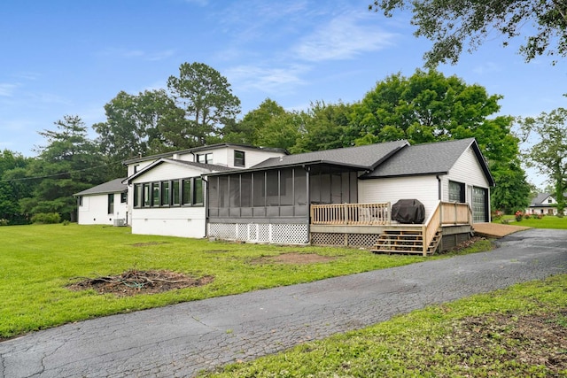 1015 Jump Off Rd, Bon Aqua, TN 37025 - view of front of house featuring a sunroom, a front yard, a shingled roof, a deck, and board and batten siding