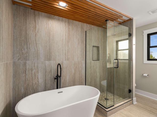 1015 Jump Off Rd, Bon Aqua, TN 37025 - bathroom featuring a freestanding tub, a stall shower, and wood finished floors