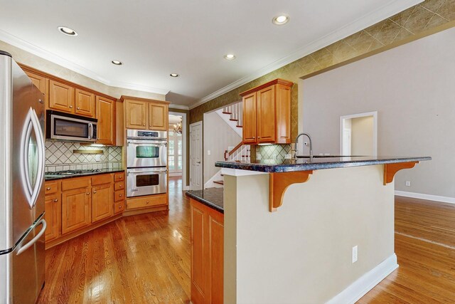 915 Joel Cheek Blvd, Franklin, TN 37064 - kitchen with appliances with stainless steel finishes, a kitchen breakfast bar, a peninsula, crown molding, and light wood-style floors