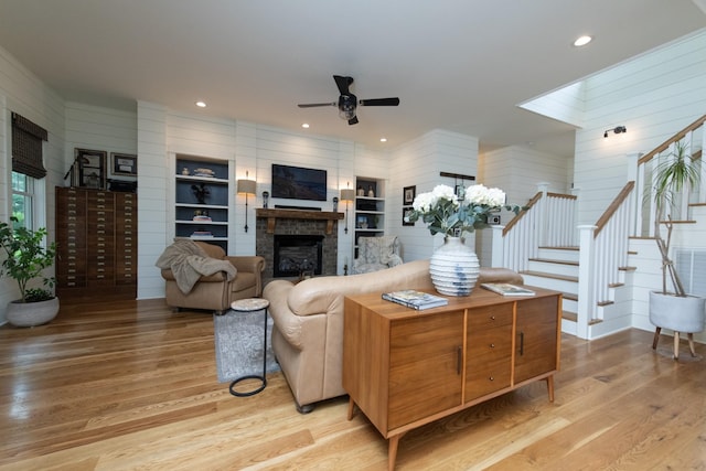 4150 Knipfer Rd, Joelton, TN 37080 - living area featuring light wood-type flooring, stairway, a stone fireplace, a ceiling fan, and wooden walls