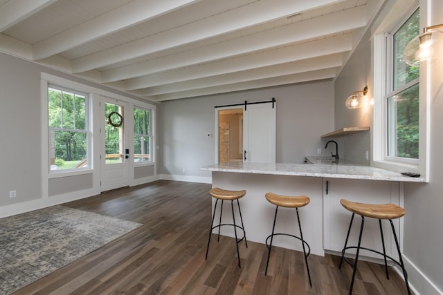 4150 Knipfer Rd, Joelton, TN 37080 - kitchen with a barn door, light stone counters, dark wood-style floors, a peninsula, and a breakfast bar