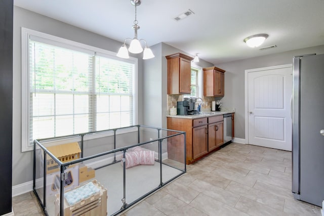 1029 Charles Thomas Dr, Clarksville, TN 37042 - kitchen with stainless steel appliances, brown cabinetry, light countertops, decorative light fixtures, and decorative backsplash
