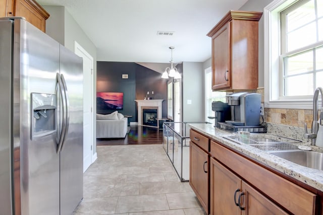 1029 Charles Thomas Dr, Clarksville, TN 37042 - kitchen featuring stainless steel fridge, brown cabinetry, a chandelier, open floor plan, and decorative backsplash