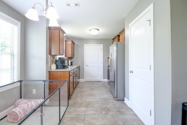 1029 Charles Thomas Dr, Clarksville, TN 37042 - kitchen featuring freestanding refrigerator, brown cabinetry, light countertops, and a chandelier