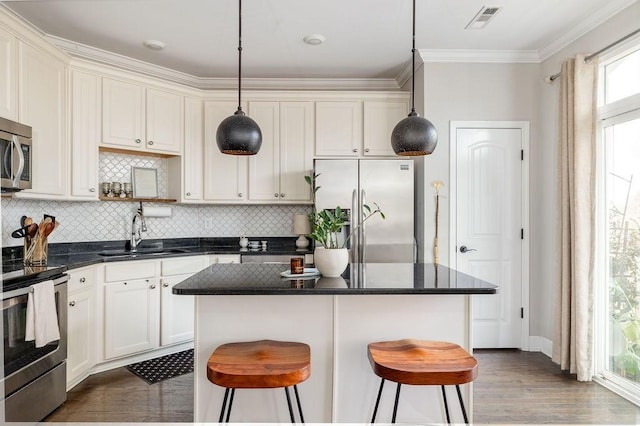 6067 Keats St, Franklin, TN 37064 - kitchen with stainless steel appliances, crown molding, decorative backsplash, a kitchen island, and a kitchen bar