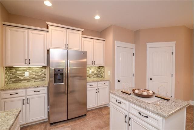 1789 Double R Blvd, Clarksville, TN 37042 - kitchen with stainless steel fridge, white cabinetry, tasteful backsplash, a kitchen island, and light stone countertops