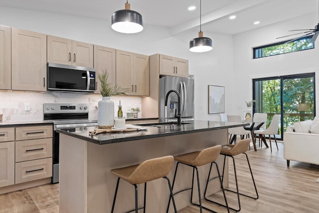 263 Eleanor Dr SW, Cleveland, TN 37311 - kitchen with appliances with stainless steel finishes, a kitchen island with sink, backsplash, a towering ceiling, and light wood-style floors