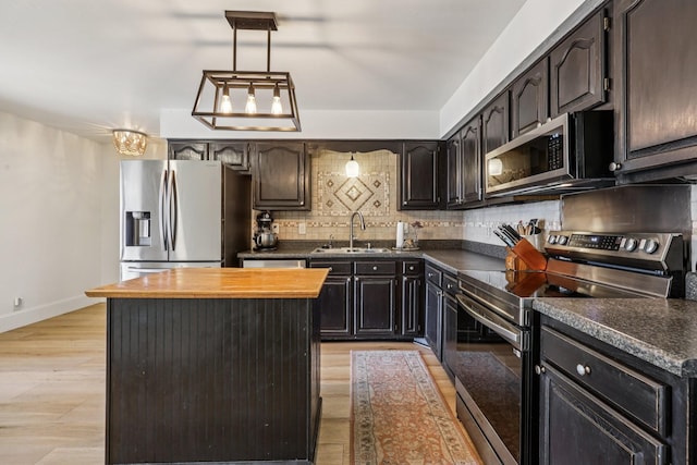 121 La View Rd, Hendersonville, TN 37075 - kitchen featuring appliances with stainless steel finishes, a center island, decorative backsplash, decorative light fixtures, and light wood-style flooring