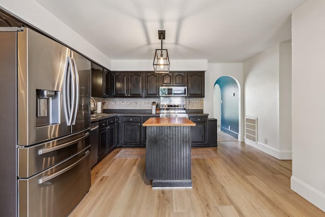 121 La View Rd, Hendersonville, TN 37075 - kitchen with appliances with stainless steel finishes, a center island, arched walkways, light wood finished floors, and decorative backsplash