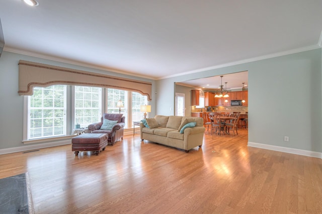 1222 Broadmoor Cir, Franklin, TN 37067 - living room with crown molding, a chandelier, and light wood-style flooring
