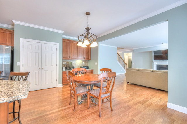1222 Broadmoor Cir, Franklin, TN 37067 - dining space featuring ornamental molding, stairway, light wood-type flooring, a fireplace, and a chandelier