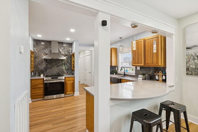 1237 Abiff Rd, Bon Aqua, TN 37025 - kitchen featuring stainless steel electric range oven, wall chimney exhaust hood, light wood-style floors, tasteful backsplash, and a kitchen breakfast bar