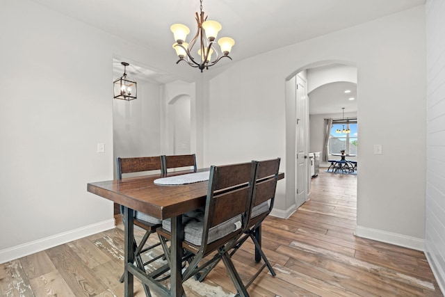 2957 Stewart Campbell Pt, Spring Hill, TN 37174 - dining space with a chandelier, arched walkways, and light wood-style floors