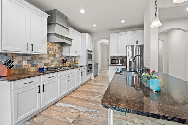 2957 Stewart Campbell Pt, Spring Hill, TN 37174 - kitchen with stainless steel appliances, arched walkways, light wood-type flooring, recessed lighting, and backsplash