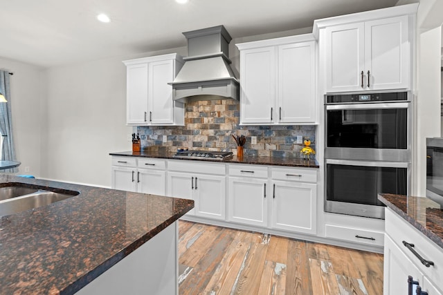 2957 Stewart Campbell Pt, Spring Hill, TN 37174 - kitchen featuring stainless steel appliances, premium range hood, white cabinetry, light wood-style flooring, and recessed lighting