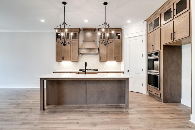 7267 Fairlawn Dr, Fairview, TN 37062 - kitchen with custom exhaust hood, a chandelier, tasteful backsplash, a kitchen island with sink, and light countertops
