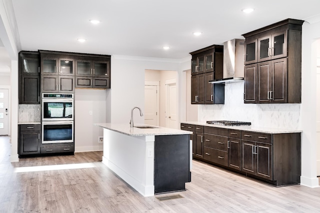 7266 Fairlawn Dr, Fairview, TN 37062 - kitchen with wall chimney range hood, appliances with stainless steel finishes, decorative backsplash, light wood-style flooring, and glass insert cabinets