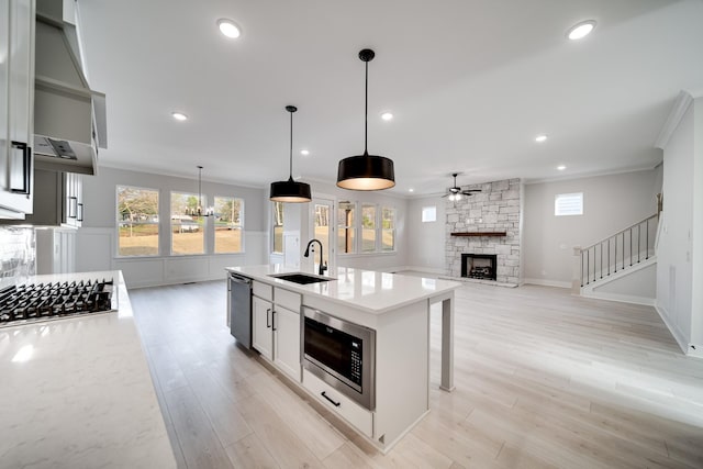 7233 Richvale Dr W, Fairview, TN 37062 - kitchen with stainless steel appliances, ceiling fan, ornamental molding, a stone fireplace, and light wood-type flooring
