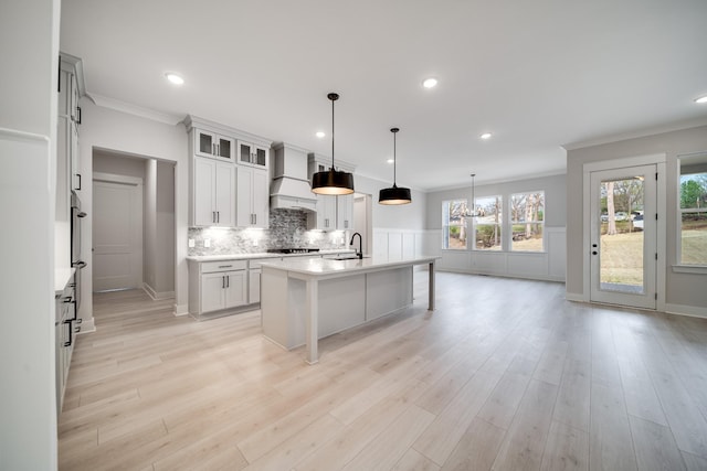 7233 Richvale Dr W, Fairview, TN 37062 - kitchen with custom exhaust hood, crown molding, light countertops, backsplash, and a center island with sink