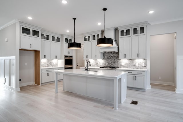 7233 Richvale Dr W, Fairview, TN 37062 - kitchen with an island with sink, gas cooktop, crown molding, light countertops, and backsplash