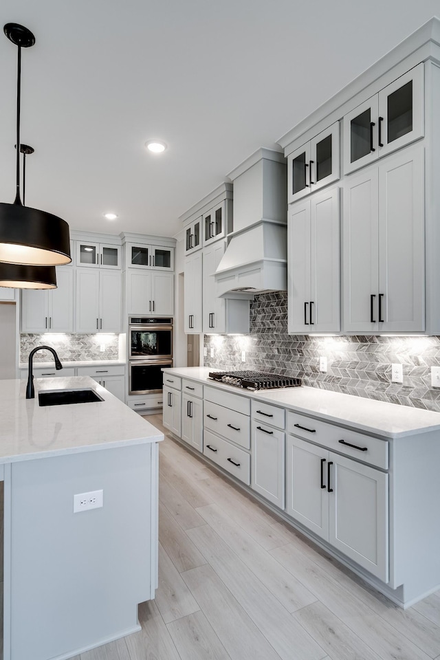 7233 Richvale Dr W, Fairview, TN 37062 - kitchen with custom range hood, decorative backsplash, appliances with stainless steel finishes, hanging light fixtures, and light wood finished floors