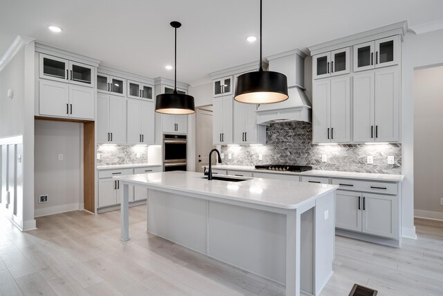 7233 Richvale Dr W, Fairview, TN 37062 - kitchen featuring appliances with stainless steel finishes, an island with sink, backsplash, light countertops, and decorative light fixtures