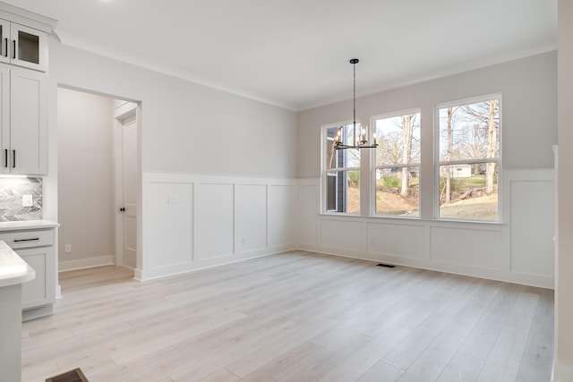 7233 Richvale Dr W, Fairview, TN 37062 - unfurnished dining area with a chandelier, a decorative wall, light wood finished floors, a wainscoted wall, and ornamental molding
