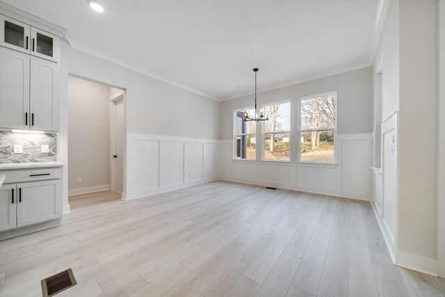 7233 Richvale Dr W, Fairview, TN 37062 - unfurnished dining area featuring a chandelier, wainscoting, light wood finished floors, ornamental molding, and a decorative wall