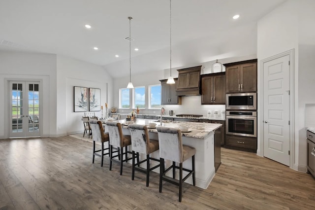 7261 Fairlawn Dr, Fairview, TN 37062 - kitchen with stainless steel appliances, a breakfast bar, wood finished floors, lofted ceiling, and a center island with sink