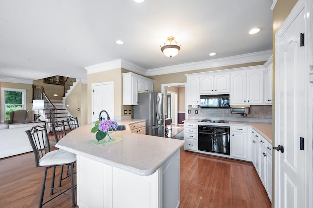 395 Glendower Pl, Franklin, TN 37064 - kitchen featuring black appliances, a peninsula, a kitchen bar, light countertops, and ornamental molding