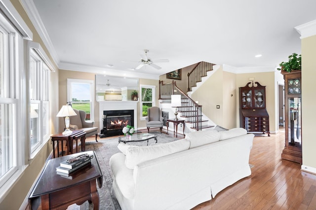 395 Glendower Pl, Franklin, TN 37064 - living room featuring a ceiling fan, a glass covered fireplace, wood-type flooring, stairway, and crown molding