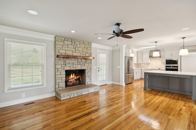 1061 Alford Rd, Murfreesboro, TN 37129 - unfurnished living room featuring light wood-style floors, crown molding, ceiling fan, plenty of natural light, and a fireplace