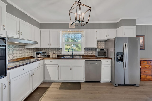 5058 New Chapel Rd, Springfield, TN 37172 - kitchen featuring appliances with stainless steel finishes, under cabinet range hood, dark countertops, white cabinets, and crown molding