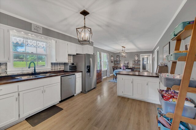 5058 New Chapel Rd, Springfield, TN 37172 - kitchen featuring appliances with stainless steel finishes, crown molding, white cabinets, light wood-style flooring, and a chandelier