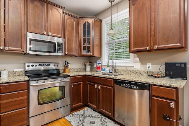 655 Lakeside Dr, Smithville, TN 37166 - kitchen with appliances with stainless steel finishes, glass insert cabinets, light stone countertops, hanging light fixtures, and light wood finished floors